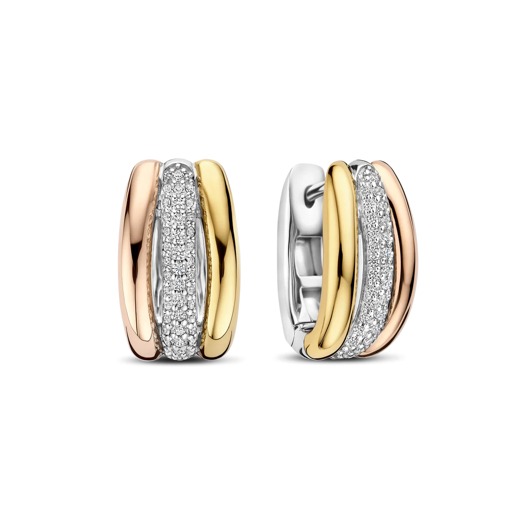 Deze Triple Circle Zirkonia Hoops zijn vervaardigd uit hoogwaardige kwaliteit 925 sterling zilver en uitgevoerd in een verfijnde combinatie van goudkleurige, ros&eacute;-goudkleurige en een met zirkonia steentjes bezette cirkel. De drie cirkels liggen elegant naast elkaar en cre&euml;ren samen een gelaagd effect met subtiel contrast. De rij zirkonia steentjes vangt het licht bij elke beweging en geeft de oorbellen een verfijnde schittering. De diameter van 15 mm zorgt voor een mooie balans tussen elegantie en draagbaarheid.

Door het tricolor ontwerp zijn deze zirkonia hoops eenvoudig te combineren met andere gouden, ros&eacute;-goudkleurigee en zilveren sieraden. De ronde, zachte vormen laten de oorbellen comfortabel om de oor vallen en geven ze een tijdloze uitstraling met een moderne twist. Deze triple circle oorbellen zijn sterk genoeg om op zichzelf te dragen, maar passen ook moeiteloos binnen een gelaagde sieradenlook. 78072TZ Circles & Cross-over oorbellen