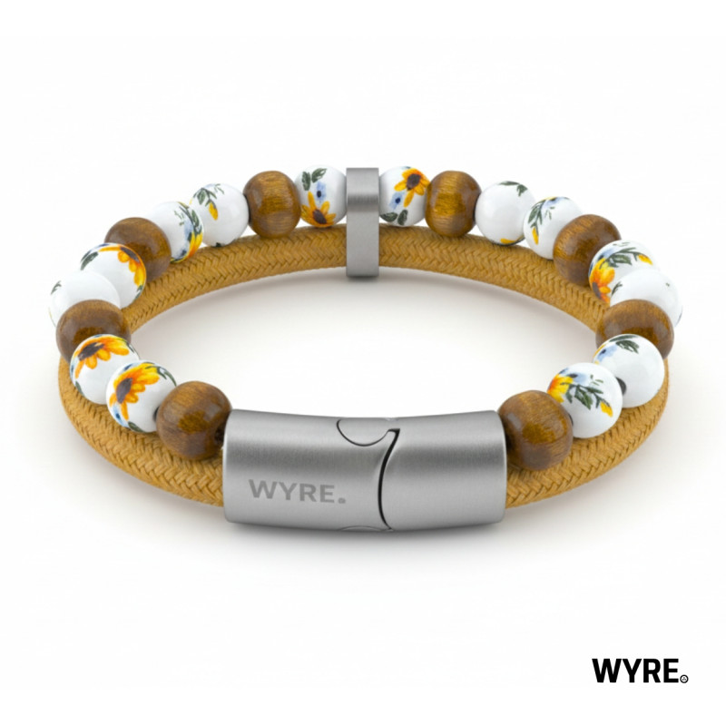 Laat je meevoeren naar warme zomerdagen, ongeacht het seizoen. Deze unieke armband combineert natuurlijke materialen met een verfijnde afwerking. De porseleinen kralen met vrolijke zonnebloemdetails vormen een prachtig contrast met de warme, aardse houten kralen.

