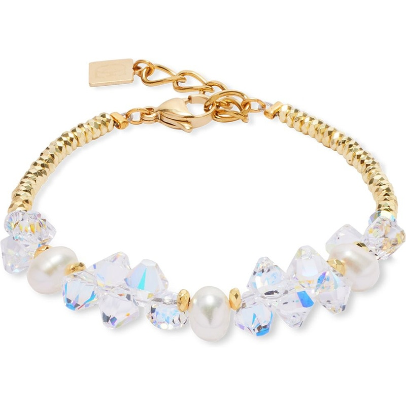 Koester de magie van tijdloze elegantie met de 1136/30-1816 Dancing Crystals & Pearls armband van Coeur de Lion. Deze betoverende armband straalt klasse en verfijning uit en balanceert op de perfecte harmonische noot van stijl en luxe. Het gouden edelstaal vouwt zich sierlijk om je pols, met een lengte die je kunt aanpassen van 18 cm tot 21 cm voor een perfecte pasvorm. De glinsterende witte en transparante Swarovski-steentjes en parels, met een breedte van 10 mm, voegen een fonkelende glamour toe en maken deze armband een schitterende aanvulling op elke juwelencollectie.