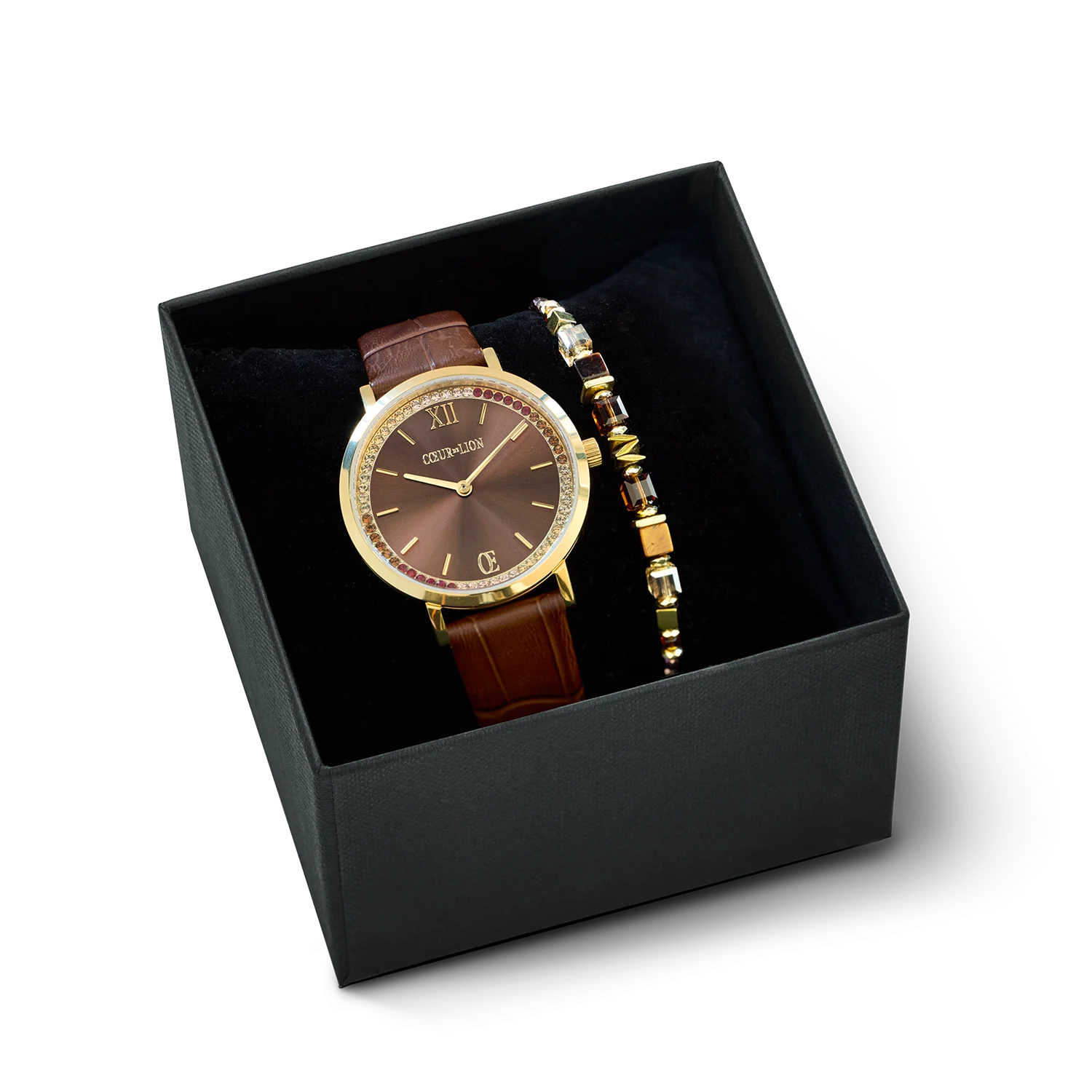 Cadeauset: Rond horloge met glinsterende bruine accenten & Armband met golvende kubusvorm en goudbruine accenten
Tijdloze elegantie ontmoet moderne verfijning: het ronde horloge met sprankelende zonnestraalmotief en bruine leren band in krokodillenprint combineert warme goudtinten met een verfijnde chocoladebruine wijzerplaat met zonnestraalmotief. Het harmonieuze kleurenpalet van bruin en geelgoud geeft dit dameshorloge een luxueuze en stijlvolle uitstraling &ndash; perfect voor zakelijk gebruik, dagelijks dragen of speciale gelegenheden.

De 34 mm tweedelige kast is vervaardigd uit hoogwaardig 316L roestvrij staal en afgewerkt met een duurzame geelgouden IP-coating. Met een slanke kasthoogte van slechts 7,5 mm zit het horloge elegant en comfortabel om de pols. Sprankelende Swarovski&reg;-kristallen accentueren de uurmarkeringen en voegen subtiele glans en exclusieve verfijning toe.