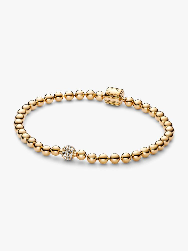 Als je stoere en edgy kralen met een elegante twist wilt dragen, kies dan voor de kralen & pav&eacute; armband van onze unieke vergulde metaalmix. De armband is ge&iuml;nspireerd op de alternatieve looks van bodypiercings en punkstijlen, maar dan met een verfijnde twist. Het sieraad bestaat uit een kralenketting met &eacute;&eacute;n grotere pav&eacute;gezette kraal en een cilindersluiting. Deze Pandora-armband kan afzonderlijk worden gedragen of worden gestapeld met andere sieraden in verschillende metaalafwerkingen voor een persoonlijke look.