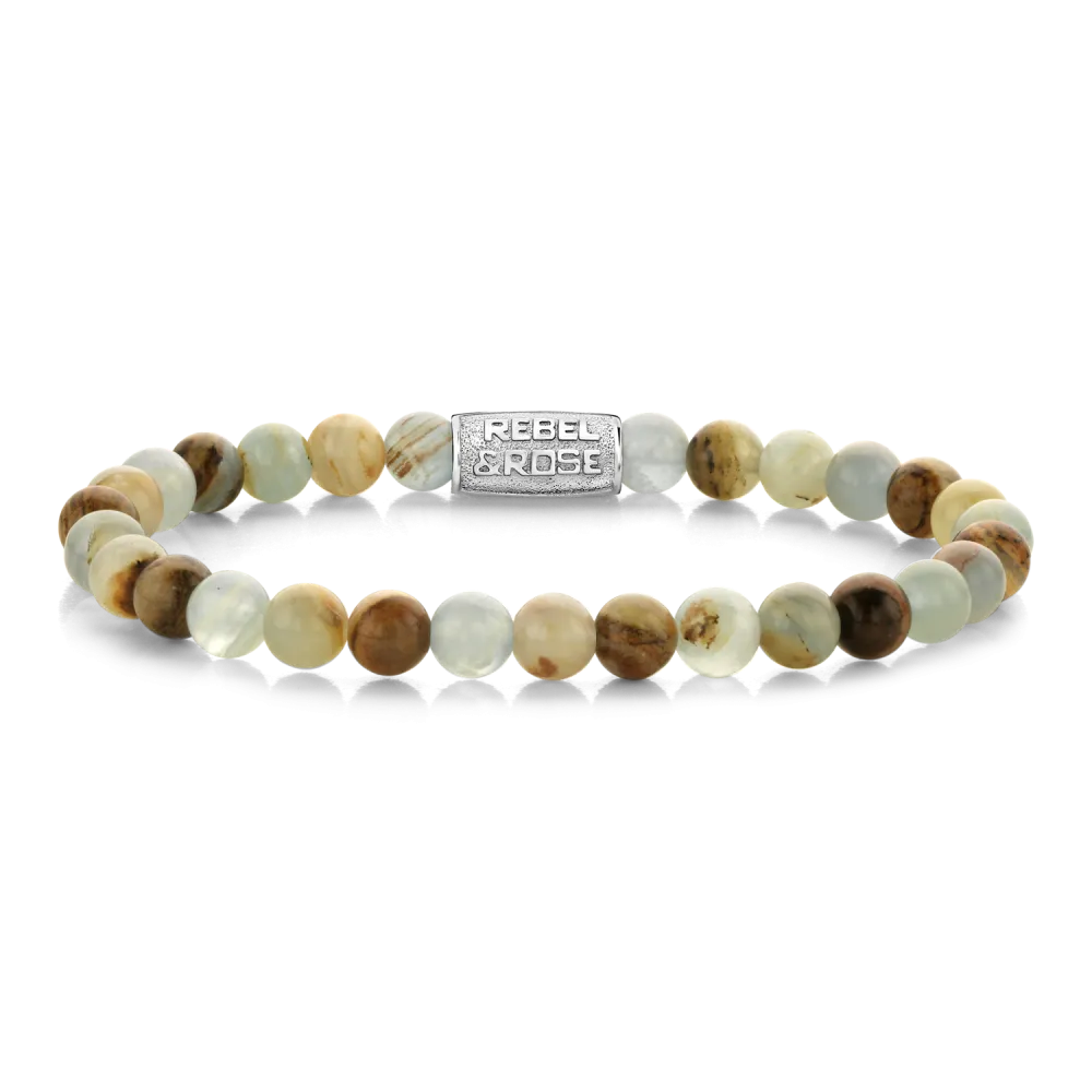 Bead armband, handgemaakt van 6 mm natuurlijke stenen kralen (Lemurian Blue Calcite) met een roestvrijstalen sluiting. De natuursteen Lemurian Blue Calcite staat bekend om zijn lichte tot diep oceaanblauwe tinten, vaak gecombineerd met witte of cr&egrave;meachtige aders en natuurlijke patronen. Elke bead is anders. De sieraden van Rebel & Rose zijn gemakkelijk te combineren met andere zilveren, leren of kralenarmbanden.