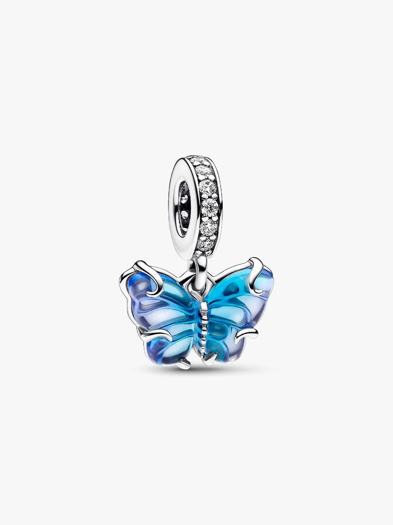 Transformeer in de beste versie van jezelf met de Blauwe Muranoglazen Vlinder Hangende Bedel. Deze hand-finished sterling zilveren bedel is afgewerkt met muranoglazen vleugels in een tweekleurig blauw kleurverloop met een opengewerkt sterlingzilver patroon op de achterkant dat door het glas heen schijnt en sterling zilveren krullen op de voorkant. Microbeads op het lijfje van de vlinder en pav&eacute; op de hanger zijn delicate details en voegen wat glans toe. Draag deze blauwe vlinder aan je styling als krachtig symbool van hoop, transformatie en een nieuw begin.
