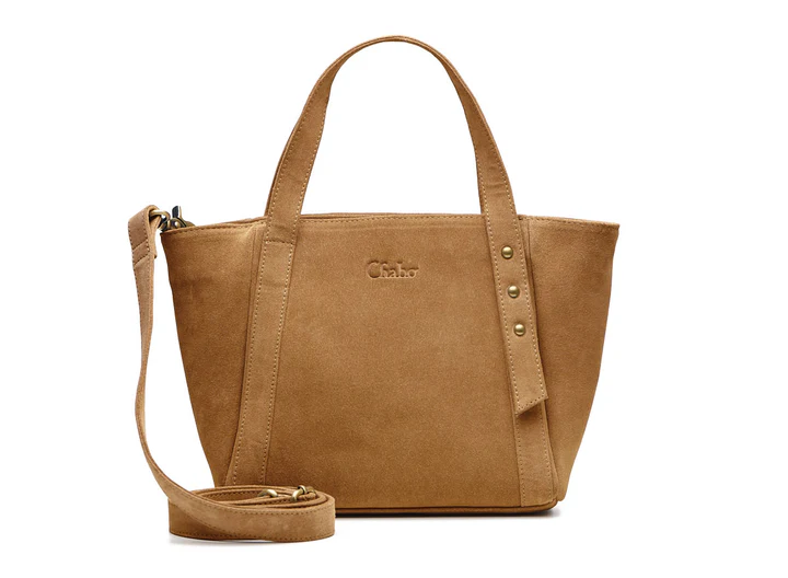 Ontdek de Suede Sydney Little Shopper

Afmeting :36 x 23 x 9 cm

Een stevige medium shopper van su&egrave;de met opvallende studs, ritssluiting, korte banden &eacute;n extra lange crossover band. Praktisch ingedeeld met insteekvakken en ritsvak
en een extra insteekvak met magneetsluiting voorop.

De Suede Sydney Little Shopper is de perfecte tas voor dagelijks gebruik. Deze mooie en stevige medium shopper combineert stijl met functionaliteit. De tas valt direct op door de studs aan de voorkant, wat zorgt voor een stoere en trendy uitstraling.

Dankzij de ritssluiting blijven al je spullen veilig opgeborgen. De korte banden maken de shopper comfortabel om in de hand of te dragen. Daarnaast wordt een extra lange crossover band meegeleverd, zodat je de tas ook crossbody kunt dragen voor extra gemak onderweg.

Aan de binnenkant biedt de Suede Sydney Little Shopper verrassend veel ruimte. Het ruime hoofdvak is praktisch ingedeeld met aan de ene kant twee insteekvakken voor kleinere essentials zoals je telefoon of sleutels, en aan de andere kant een afsluitbaar ritsvak voor waardevolle spullen.

Deze su&egrave;de shopper is ideaal voor werk, shoppen of een dagje uit en past moeiteloos bij iedere outfit.