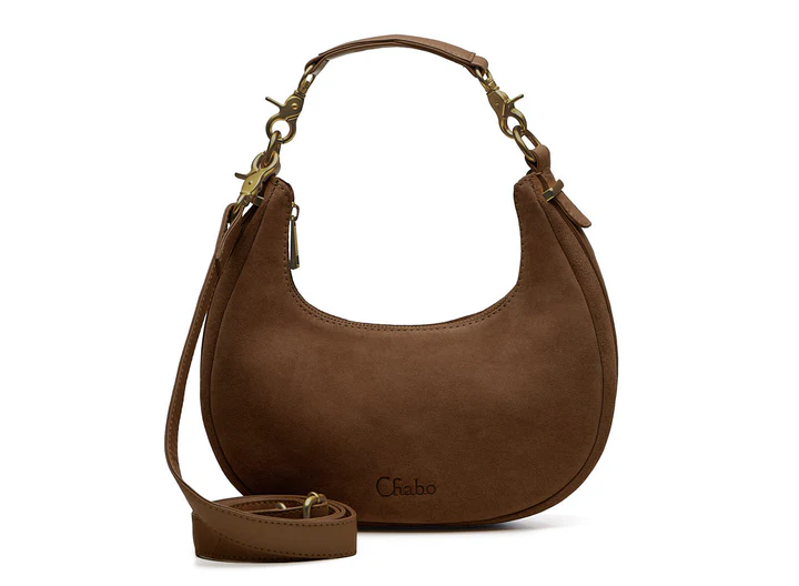 Ontdek de leren Sydney Shoulderbag

Afmeting 26 x 14 x 7 cm

Een fashionable ronde suede tas met leren bies, afneembaar leren handvat en extra lange crossover band. Praktisch ingedeeld met insteekvak en ritsvak.

De Sydney Shoulderbag is een stijlvolle en fashionable tas die iedere outfit een trendy uitstraling geeft. Het ronde model in zacht leer zorgt voor een elegante en moderne look, terwijl de leren bies rondom de tas zorgt voor een luxe afwerking.

De tas is voorzien van een leren afneembaar handvat, waardoor je hem stijlvol als schoudertas kunt dragen. Liever handsfree onderweg? Verwissel het korte handvat eenvoudig voor de extra lange crossover band en draag de tas comfortabel crossbody.
Ook aan de binnenkant is de Sydney Shoulderbag praktisch ingedeeld.

De tas beschikt over een handig insteekvak aan de ene kant voor kleinere essentials zoals je telefoon of lipgloss. Aan de andere kant bevindt zich een afsluitbaar ritsvak voor het veilig opbergen van waardevolle spullen.

Dankzij het compacte maar ruime ontwerp is deze  schoudertas perfect voor dagelijks gebruik, een avondje uit of een dag shoppen.

