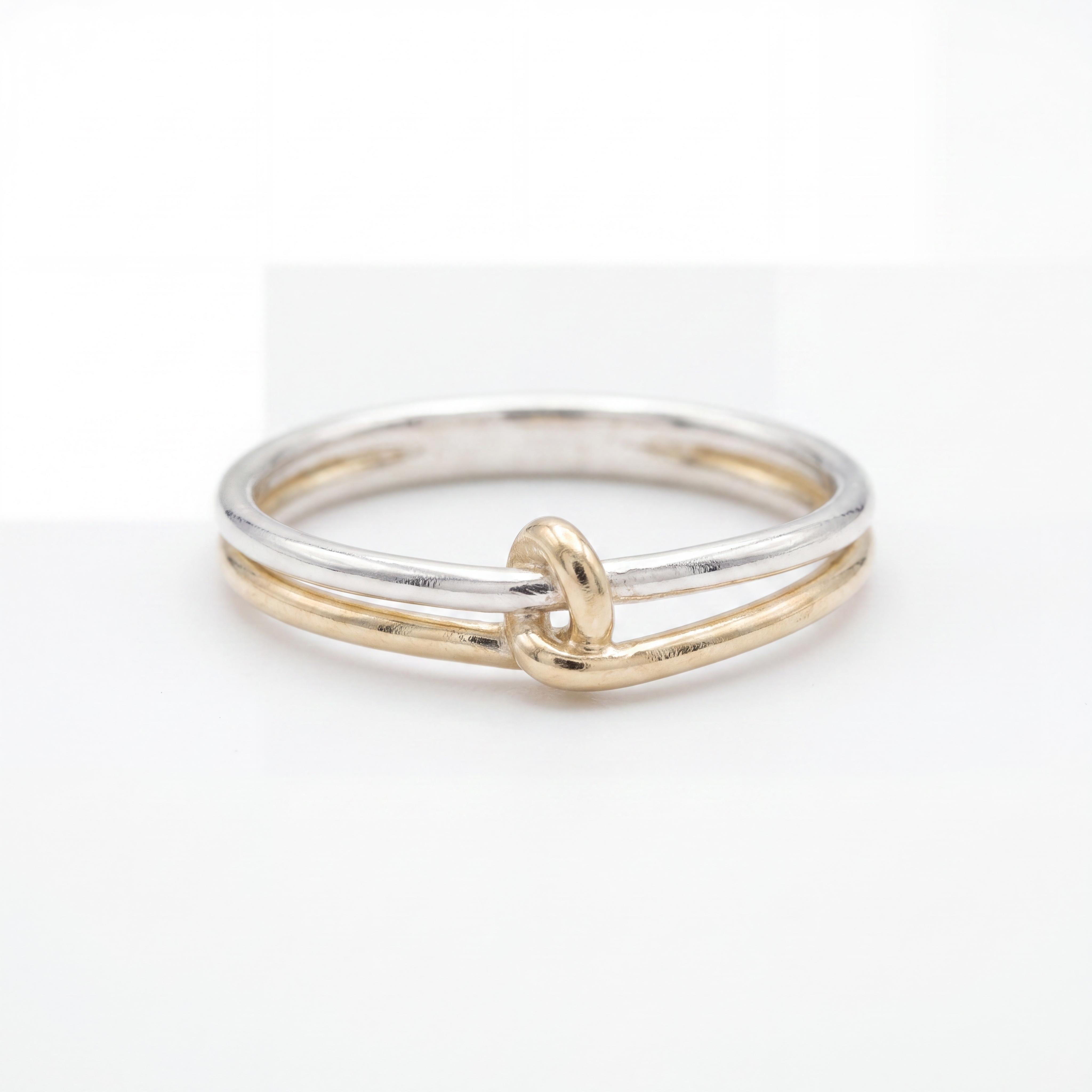 Ontdek een meesterwerk van puur vakmanschap en symbolische schoonheid. Deze exclusieve handgemaakte bicolor ring van 14 karaat goud van Juwelier Rijk Amsterdam is een sieraad met een verhaal. Twee fijne banen &ndash; de &eacute;&eacute;n van glanzend witgoud, de ander van warm geelgoud &ndash; komen in het centrum op elegante wijze samen in een subtiele, handgesmede knoop. Dit unieke ontwerp symboliseert eeuwige verbondenheid, liefde of vriendschap.

Massieve kwaliteit voor dagelijks gebruik
Bij Juwelier Rijk geloven we dat ware luxe comfortabel en duurzaam moet zijn. Deze tweekleurige ring is volledig massief vervaardigd uit hoogwaardig 14 karaat goud. Dankzij de solide constructie en de verfijnde afwerking is de ring uitermate geschikt voor dagelijks gebruik. Of u hem nu solo draagt als subtiele eyecatcher of combineert met uw favoriete aanschuifringen; dit handgemaakte sieraad behoudt altijd zijn stevigheid en schittering.