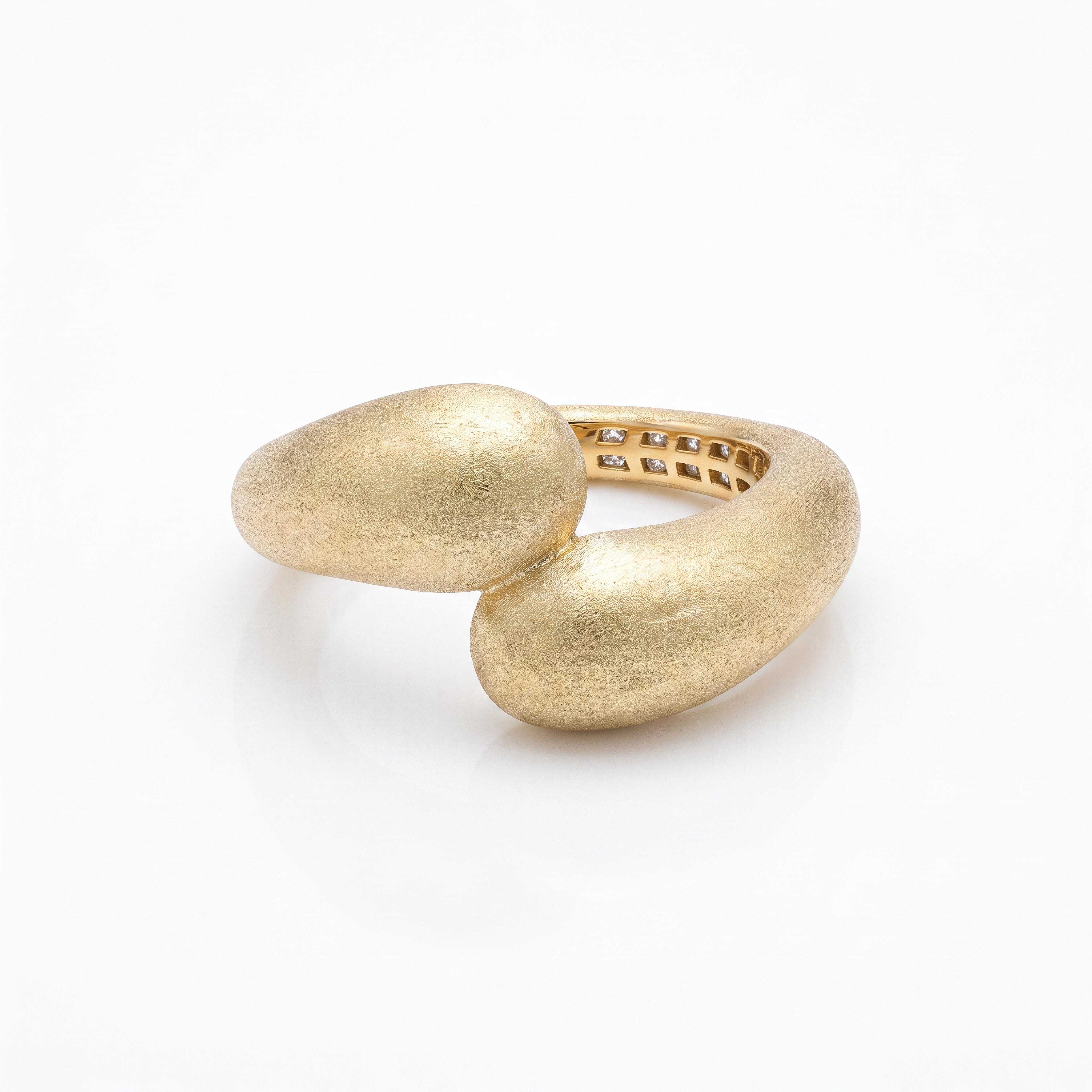 Laat je betoveren door ring 'The Art': een exclusief, handgemaakt juweel van 14 karaat goud met een unieke, organische vormgeving. De ring heeft een verfijnde, gediamanteerde afwerking voor een luxe, fluweelzachte glans. Aan de binnenzijde schuilt een subtiel geheim: een rij verfijnd gezette stenen die zorgen voor een schitterend detail bij elke beweging. Een tijdloos statement piece van pure ambacht.
