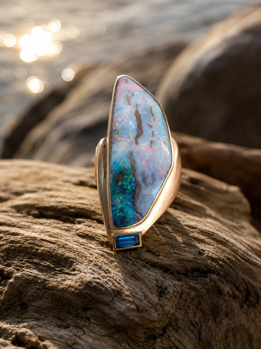 Dieser Ring in Rotgold 750 gefertigt, einem Boulder Opal mit 25,96ct und einem blauem Turmalin, besticht durch seine edlen Materialien und einzigartigen Farbnuancen. Ideal als Statement-Schmuckst&uuml;ck getragen, zieht er Blicke auf sich. Perfekt f&uuml;r besondere Anl&auml;sse oder um allt&auml;gliche Outfits aufzuwerten. Ein Must-Have f&uuml;r Schmuckliebhaber, die Exklusivit&auml;t und Stil sch&auml;tzen.