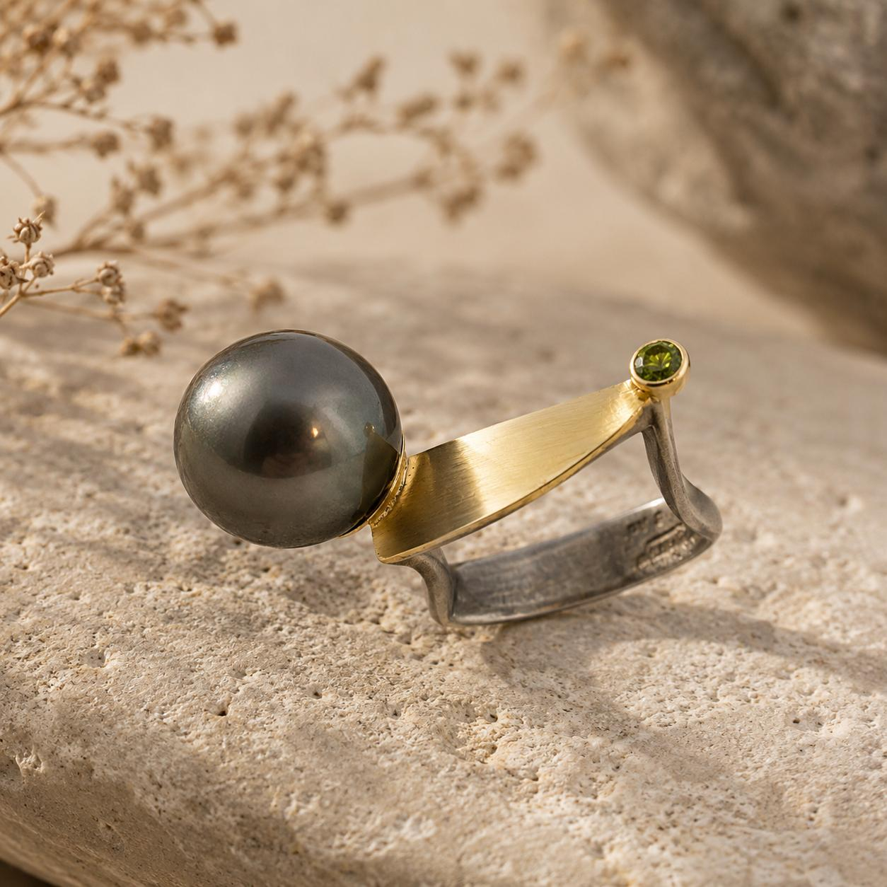 Dieser elegante Ring aus der Kategorie Schmuck besticht durch eine harmonische Kombination aus Silber (Ag) und Gold (Au), verziert mit einer Tahiti-Perle und funkelnden gr&uuml;nen Brillanten. Ideal f&uuml;r besondere Anl&auml;sse oder als stilvolles Accessoire im Alltag. Tragen Sie ihn an Ihrem Lieblingsfinger, um jedem Outfit eine luxuri&ouml;se Note zu verleihen.