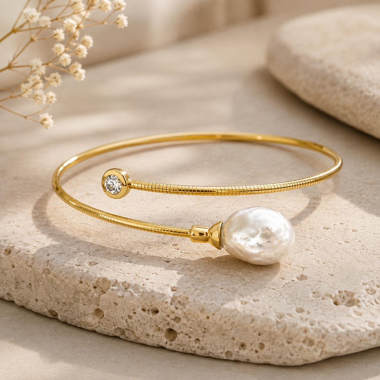 Dieser exquisite Armschmuck vereint klassischen Charme mit modernem Design. Gefertigt aus strahlendem Gelbgold 750 beginnt das Schmuckst&uuml;ck an einem Ende mit einer atemberaubenden, facettierten Barockperle und m&uuml;ndet in einen 0,16ct gro&szlig;en Brillanten Wsi. Der flexible und &auml;u&szlig;erst robuste Titankern macht dieses Schmuckst&uuml;ck zu einem absolut alltagstauglichen, t&auml;glichen Begleiter. Die einzigartige Form und der subtile Glanz der Perle machen diesen Armschmuck zu einem wahren Blickfang. Ein zeitloses Accessoire, das Eleganz und Stil verk&ouml;rpert. 