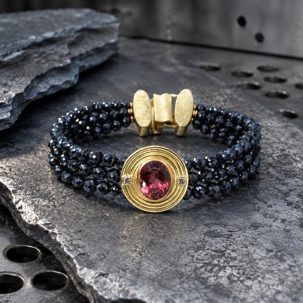 Exklusives Armband mit Turmalin & Brillanten
Ein ausdrucksstarkes Unikat mit au&szlig;ergew&ouml;hnlicher Pr&auml;senz: Facettierte, tiefdunkle Diamantperlen bilden einen spannenden Kontrast zur handgearbeiteten Fassung aus 18 Karat Gold. Im Mittelpunkt leuchtet ein beeindruckender Turmalin von 13,2 ct., flankiert von zwei funkelnden Brillanten.
Mit einer L&auml;nge von ca. 190 mm verbindet das Armband kraftvolle Eleganz mit feinster Goldschmiedekunst &ndash; ein besonderes Schmuckst&uuml;ck, das sowohl pur als auch zum eleganten Abendlook wirkt.