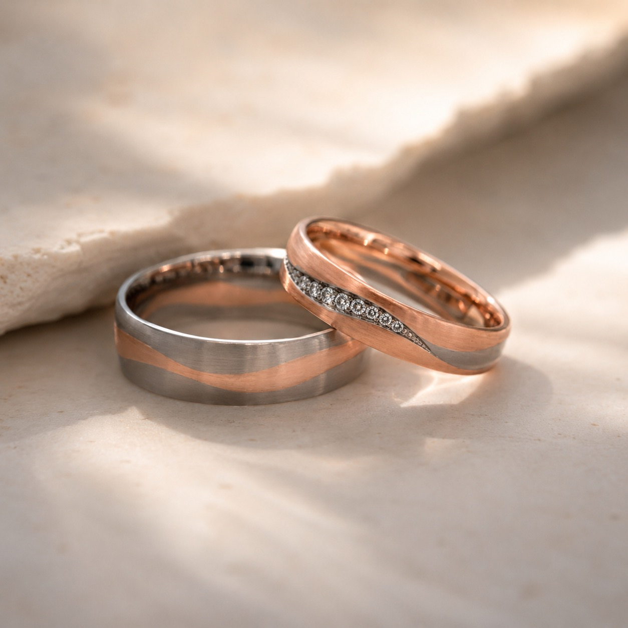 Zwei Goldt&ouml;ne &ndash; eine gemeinsame Linie
Diese au&szlig;ergew&ouml;hnlichen Trauringe aus Ros&eacute;- und Wei&szlig;gold 750 verbinden zwei unterschiedliche Goldfarben zu einem harmonischen Ganzen. Eine sanft geschwungene Linie zieht sich durch beide Ringe und macht ihre Zusammengeh&ouml;rigkeit auf den ersten Blick sichtbar.
Beim breiteren Ring setzt sich das warme Ros&eacute;gold als flie&szlig;endes Band vom k&uuml;hlen Wei&szlig;gold ab. Der schmalere Ring greift diese Formensprache auf und interpretiert sie feiner: Hier wird die geschwungene Linie zus&auml;tzlich von Brillanten begleitet, die dem Ring ein dezentes, lebendiges Funkeln verleihen.
Besonders reizvoll ist das Wechselspiel der Materialien. Warmes Ros&eacute;gold trifft auf zur&uuml;ckhaltendes Wei&szlig;gold, klare Fl&auml;chen auf eine organisch verlaufende Gestaltung. So entstehen zwei eigenst&auml;ndige Ringe, die dennoch unverkennbar miteinander verbunden sind.
Ein individuell gefertigtes Trauringpaar f&uuml;r zwei Menschen, die zusammengeh&ouml;ren, ohne gleich sein zu m&uuml;ssen.
Ros&eacute;gold 750 &middot; Wei&szlig;gold 750 &middot; Brillanten
Handgefertigt im KISSNER Meisteratelier.
