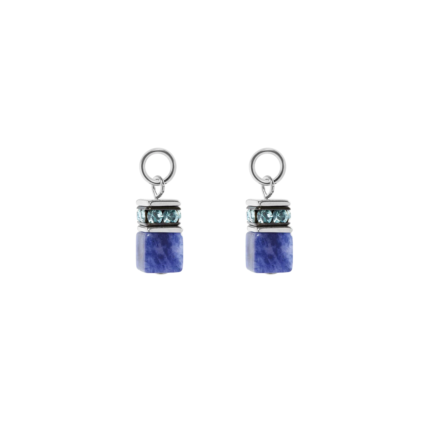De EAR ME UP bedel GeoCUBE&reg; in zilverblauw is een transparante bedel die ontworpen is om aan oorringen te bevestigen. De bedel combineert koele blauwe tinten met een moderne, lichte uitstraling en ingetogen elegantie. Sodaliet brengt rust en structuur in het ontwerp, terwijl sprankelende kristallen subtiele accenten toevoegen en zilverkleurige details de look een moderne en strakke uitstraling geven. De edelsteen symboliseert helderheid, inspiratie en innerlijke rust, waardoor je stijl een evenwichtige en stijlvolle aura krijgt. Perfect te combineren met GeoCUBE&reg; kettingen, oorbellen en armbanden.