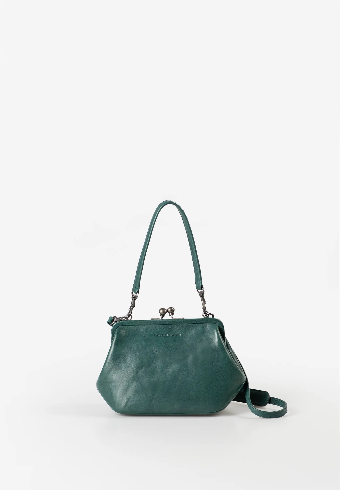 Mrs. Pizelle handtas & schoudertas &ndash; Green Jewel
De Mrs. Pizelle uit de collectie Grandma's Luxury Club is een stijlvolle tas met een uitgesproken retro-uitstraling. Gemaakt van premium rundleer met een karakteristieke, golvende structuur heeft deze compacte tas een opvallende bolle vorm en een unieke vintage look.
De elegante clipsluiting en de ruime beugelopening geven Mrs. Pizelle een nostalgische charme &eacute;n maken het gemakkelijk om snel bij je dagelijkse essentials te komen. Dankzij de verschillende draagmogelijkheden is deze tas geschikt voor zowel een casual dagje uit als een bijzondere gelegenheid.

Veelzijdig te dragen
Mrs. Pizelle kan op verschillende manieren worden gedragen. Gebruik het korte, afneembare handvat om de tas klassiek in de hand te dragen of bevestig de afneembare, verstelbare schouderband voor een comfortabele crossbodylook. De schouderband is voorzien van een praktisch schouderpad voor extra draagcomfort.
Ondanks het compacte formaat is het interieur slim georganiseerd. Een steekvak, ritsvak, kaartenvak en sleutelband houden je belangrijkste spullen overzichtelijk op hun plek. Het uitneembare extra tasje biedt bovendien flexibele extra opbergruimte.

De lichte, gestreepte voering en meegeleverde stofzak onderstrepen de hoogwaardige afwerking van deze bijzondere leren tas.

Kenmerken
Stijlvolle handtas en crossbodytas
Gemaakt van premium rundleer
Karakteristieke golvende lederstructuur
Hoofdvak met clipsluiting
Grote beugelopening
Intern steekvak
Intern ritsvak
Kaartenvak
Sleutelband
Uitneembaar extra tasje
Kort, afneembaar handvat
Afneembare en verstelbare schouderband
Schouderband met comfortabel schouderpad
Lichte, gestreepte voering
Inclusief stofzak
Specificaties
Artikelnummer: 40284-119
Kleur: Green Jewel
Materiaal: Premium rundleer
Gewicht: 0,34 kg
Afmetingen (L x D x H): ca. 24 x 9,5 x 15 cm
Inhoud: ca. 1,5 liter
Schouderband: ca. 125&ndash;140 cm
Collectie: Grandma's Luxury Club
