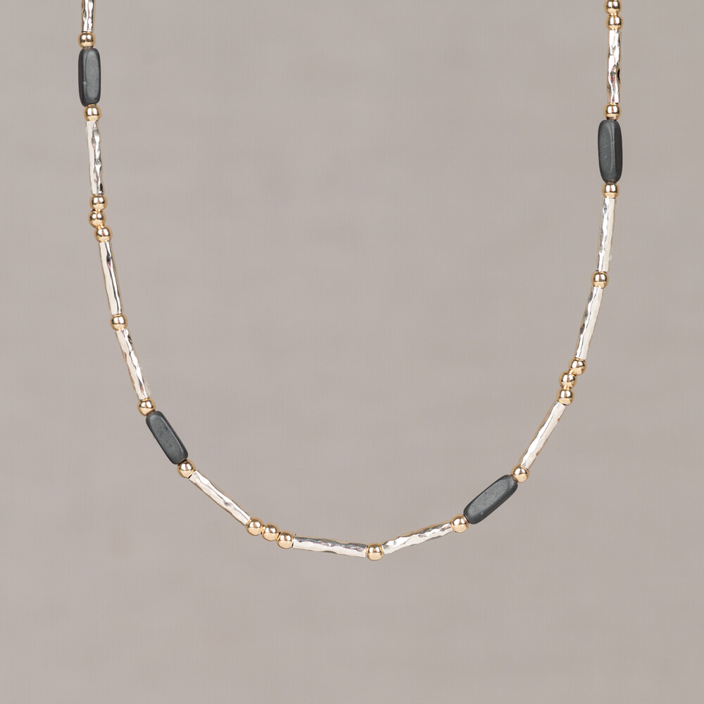 Dit collier maakt deel uit van de Tubes collectie en is opgebouwd uit smallere buisjes die zorgen voor een slanke, strakke vormgeving. Het materiaal is 925 sterling zilver in combinatie met Goldfilled, ook aangeduid als Touch of Gold. Het kleurcontrast wordt verzorgd door Hematiet, een metaalachtige en ondoorzichtige edelsteen met een kenmerkende donkere glans in grijze tot zwarte tinten. Hematiet is een ijzerrijke edelsteen die bekend staat om zijn opvallende metallic uitstraling. Edelstenen zijn natuurproducten; kleur en afmeting kunnen afwijken van de afbeelding. Jeh Jewels is een Nederlands sieradenmerk, opgericht in 1991, met tijdloze ontwerpen die al jarenlang tot de collectie behoren.