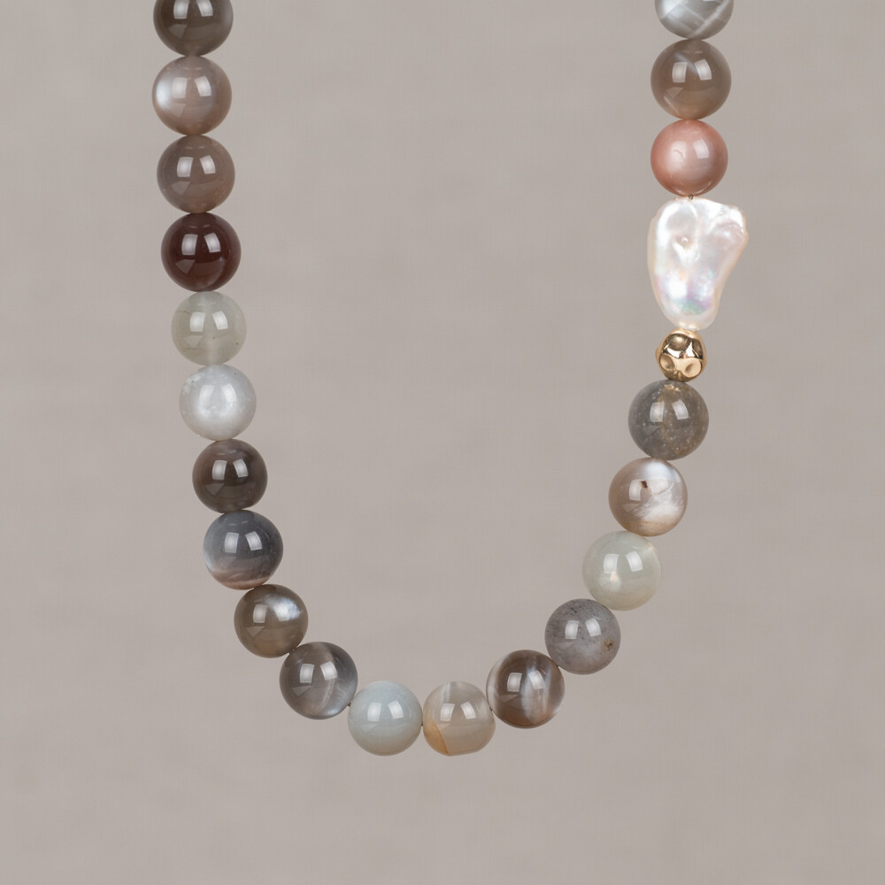 Dit collier maakt deel uit van de Candy Gems collectie, een onderdeel van de Mix & Match lijn van Jeh Jewels. Het collier is met de hand geregen en combineert maansteen en parel in bruine, oranje en witte tinten. Grijze en zwarte accenten zorgen ervoor dat het collier ook te dragen is met zwarte outfits. Een Goldfilled balletje voegt een Touch of Gold toe aan het geheel. Maansteen is een halfedelsteensoort met een karakteristieke glans en komt voor in verschillende kleurvariaties. Parel is een organisch materiaal dat van nature voorkomt in warme en koele tinten. Edelstenen zijn natuurproducten; kleur en formaat kunnen afwijken van de afbeelding.