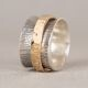 Brede ring in 925 sterling zilver met een geoxideerde afwerking. De streepjesbewerking op het zilver wordt met de hand aangebracht, waardoor elk stuk iets kan afwijken van een ander. Om de ring is een brede Goldfilled ring geplaatst die het geheel een uitgesproken karakter geeft. De ring maakt deel uit van de Touch of Gold collectie.