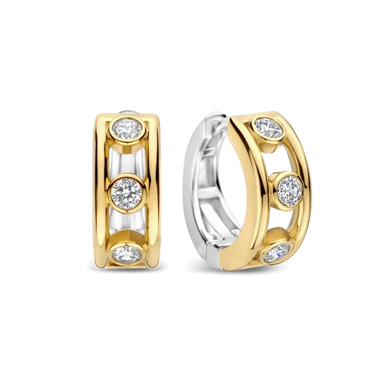 Deze Open Cirkel Zirkonia Hoops combineren een modern ontwerp met verfijnde sprankeling. De oorbellen zijn vervaardigd uit hoogwaardige kwaliteit 925 sterling zilver en goudkleurig verguld. De hoops hebben een open ruimte tussen de twee buitenkanten, waarin ronde zirkonia steentjes zijn geplaatst in ronde zettingen met open ruimtes ertussen. Dit geeft de oorbellen een open en luchtig effect en zorgt voor een elegante, eigentijdse uitstraling. Draag deze goudkleurig vergulde hoops met zirkonia solo als stijlvolle eyecatcher of combineer ze met andere oorbellen voor een persoonlijke ear party. Het open ontwerp met fonkelende details past moeiteloos bij zowel een dagelijkse look als een meer geklede outfit.