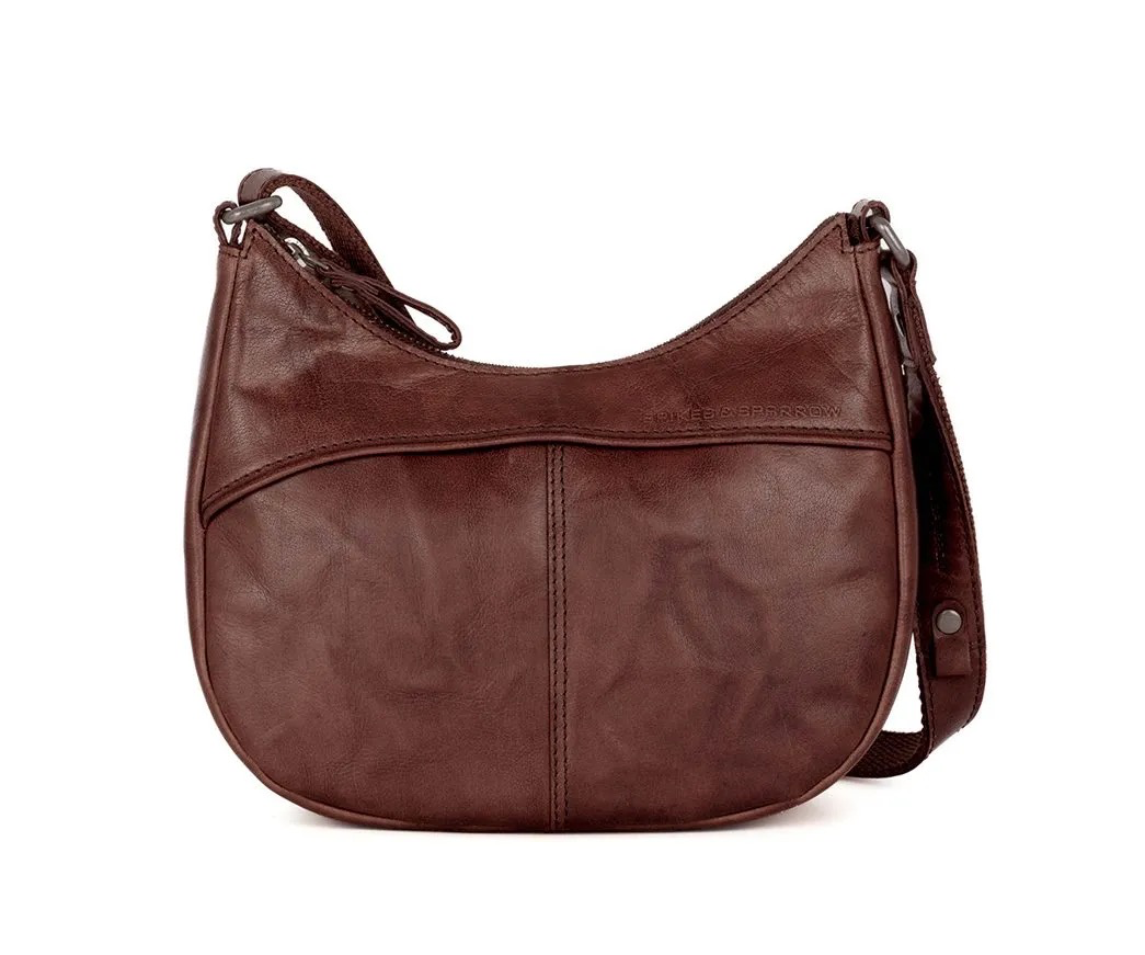 Leren schoudertas donkerbruin &ndash; compacte Spikes & Sparrow tas
Tijdloos, vrouwelijk en n&eacute;t even anders. Deze compacte Spikes & Sparrow schoudertas in donkerbruin combineert een elegante uitstraling met de stoere, karaktervolle look van echt Bronco leer. Het verfijnde lijnenspel aan de voorzijde geeft de tas een eigentijdse uitstraling, terwijl het leer zorgt voor die herkenbare, casual uitstraling van Spikes & Sparrow.
Aan de voorzijde bevindt zich een verborgen insteekvoorvak met magneetsluiting. Ideaal voor spullen die je snel bij de hand wilt hebben, zoals je telefoon, sleutels of zonnebril. Het hoofdvak sluit met een rits en aan de achterzijde vind je nog een praktisch ritsvak voor extra opbergruimte.

Compact en praktisch
Ondanks het compacte formaat biedt deze leren schoudertas voor dames voldoende ruimte voor je dagelijkse essentials. Binnenin vind je een ritsvak, een handig insteekvak en een sleutellusje. Zo houd je kleine spullen overzichtelijk en snel vindbaar.
De vaste, lange schouderband is verstelbaar, waardoor je de tas comfortabel op de gewenste lengte kunt dragen. Of je nu onderweg bent naar je werk, een dagje gaat shoppen of een middagje de stad in gaat: deze donkerbruine leren tas is een stijlvolle en praktische metgezel voor iedere dag.

Productdetails
Merk: Spikes & Sparrow
Kleur: Donkerbruin
Materiaal: Bronco leer
Afmetingen: 24,5 x 8 x 21 cm
Exterieur: hoofdvak met rits en achtervak met rits
Voorzijde: verborgen insteekvoorvak met magneetsluiting
Interieur: ritsvak, insteekvak en sleutellusje
Schouderband: vaste, lange verstelbare schouderband
Draagwijze: als schoudertas
Deze donkerbruine leren schoudertas van Spikes & Sparrow is ideaal voor wie houdt van een compacte tas met een vrouwelijke uitstraling, stoere leren details en een praktische indeling.