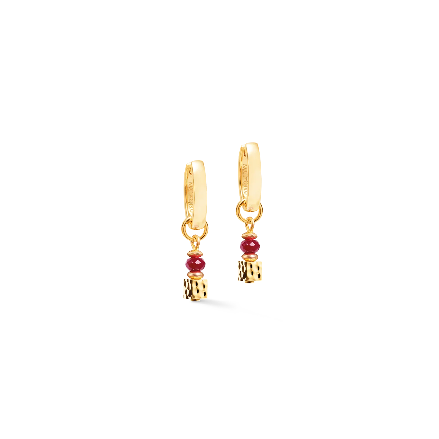 De creolen 'Hammered Cube Ruby Gold' combineren strakke geometrie met de onmiskenbare vormentaal van COEUR DE LION. Een fijn gehamerde kubus en gefacetteerde, gekleurde jadekralen vormen de kenmerkende, afneembare hanger, wat zorgt voor een elegante compositie van levendig robijnrood en warme goudtinten. Het minimalistische silhouet geeft deze hoogwaardige designoorbellen een tijdloos karakter dat zowel bij een alledaagse outfit als bij speciale gelegenheden past. De hanger is in enkele eenvoudige stappen te verwijderen, waardoor het ontwerp twee verschillende looks biedt. Met de hanger vormen de creolen een verfijnd, eigentijds statement; zonder hanger zijn het ingetogen, minimalistische oorringen. Dankzij deze veelzijdigheid zijn ze een elegante keuze voor uiteenlopende stijlen, of ze nu los worden gedragen of worden gecombineerd met de bijpassende ketting en armband tot een perfect op elkaar afgestemde sieradenset. Gekleurde jade, goudkleurige hematiet en hoogwaardig goudkleurig roestvrij staal combineren natuurlijke schoonheid met eigentijds vakmanschap en een tijdloos ontwerp.