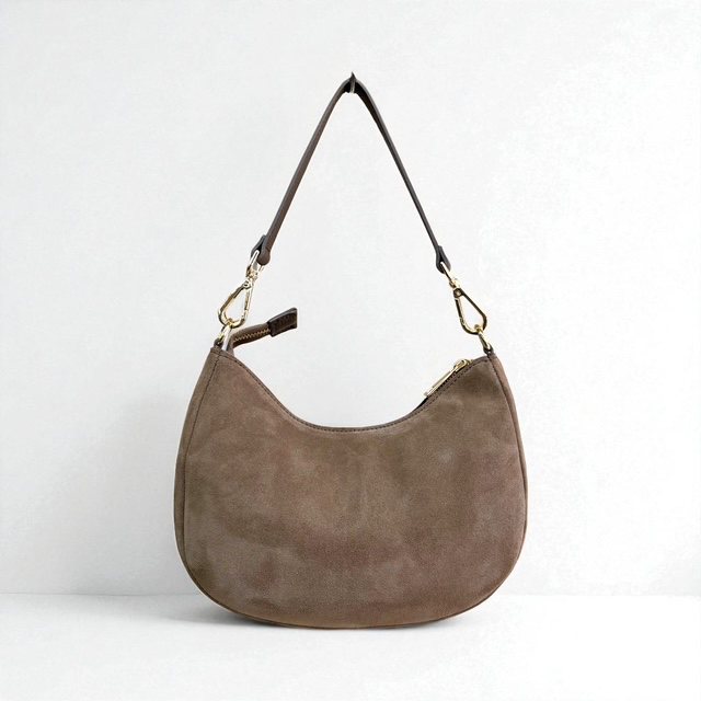 Su&egrave;de schoudertas met korte en lange schouderriem
Deze stijlvolle su&egrave;de schoudertas combineert een zachte, luxe uitstraling met praktisch draagcomfort. De tas is voorzien van een gladde korte schouderriem, waarmee je haar elegant en comfortabel over de schouder draagt.
Daarnaast wordt de tas geleverd met een lange, afneembare en verstelbare schouderriem. Hierdoor kun je de tas eenvoudig aanpassen aan jouw persoonlijke stijl en zowel over de schouder als crossbody dragen.

De tas sluit aan de bovenzijde met een ritssluiting. Het hoofdvak biedt voldoende ruimte voor je dagelijkse essentials. Binnenin vind je een extra ritsvak en twee steekvakken, zodat je kleinere spullen overzichtelijk kunt opbergen.

Productdetails:

Su&egrave;de schoudertas voor dames
Gladde korte schouderriem
Lange, afneembare en verstelbare schouderriem
Te dragen over de schouder of crossbody
Toprits
E&eacute;n ruim hoofdvak
Binnenvak met ritssluiting
Twee steekvakken
Geen voorvak
Afmetingen: 16 cm hoog x 26 cm breed x 9 cm diep
Een elegante en veelzijdige su&egrave;de tas voor dames, perfect voor dagelijks gebruik. De combinatie van het zachte su&egrave;de en de verschillende draagmogelijkheden maakt deze tas een stijlvolle aanvulling op iedere garderobe.