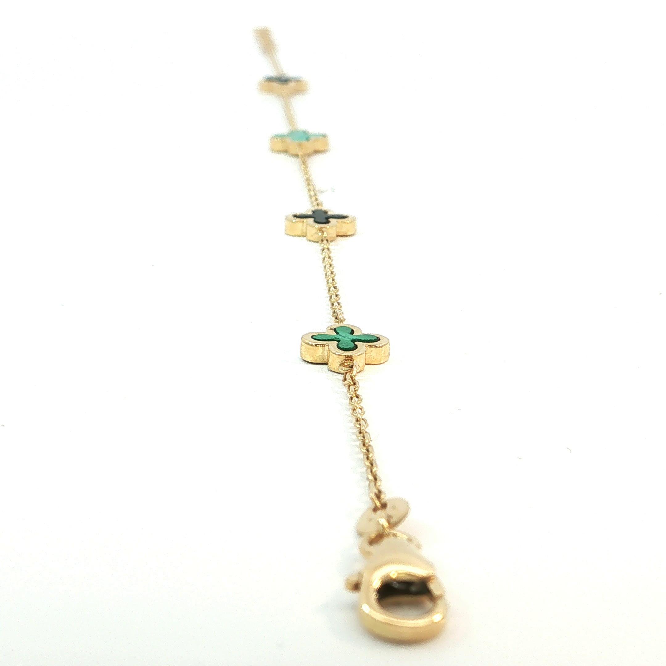Elegante armband in 18KT goud, verfijnd afgewerkt met vier klavervormige elementen. Twee groene en twee zwarte klavertjes zorgen voor een stijlvol contrast en een unieke uitstraling. Een tijdloos juweel dat luxe, elegantie en symboliek perfect combineert.