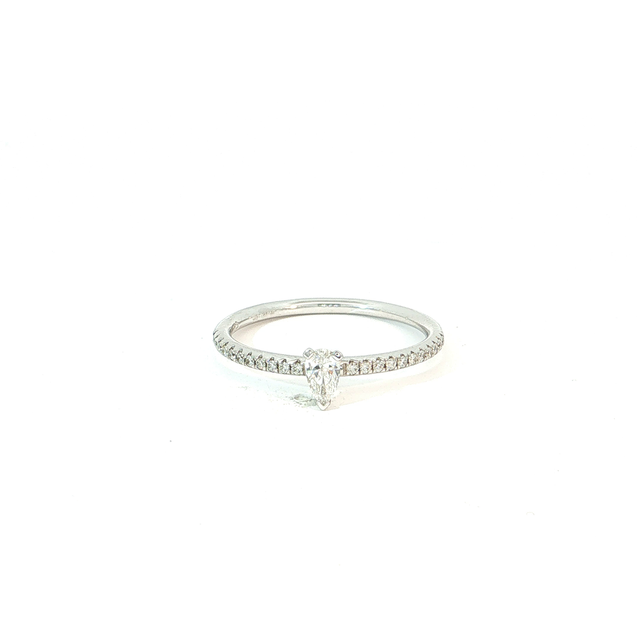 Een elegante ring met een speelse, vrouwelijke twist. De blikvanger is de peervormige diamant, een bijzondere slijpvorm die de vinger optisch verlengt en meteen een verfijnde uitstraling geeft.
De fijne ringband in 18 kt witgoud is bezet met een rij fonkelende briljanten die de centrale steen extra laten schitteren. Het resultaat is licht, elegant en net iets anders dan de klassieke solitair.
Een romantische verlovingsring met karakter &mdash; voor wie houdt van verfijning, schittering en een ontwerp dat opvalt zonder te overdrijven.