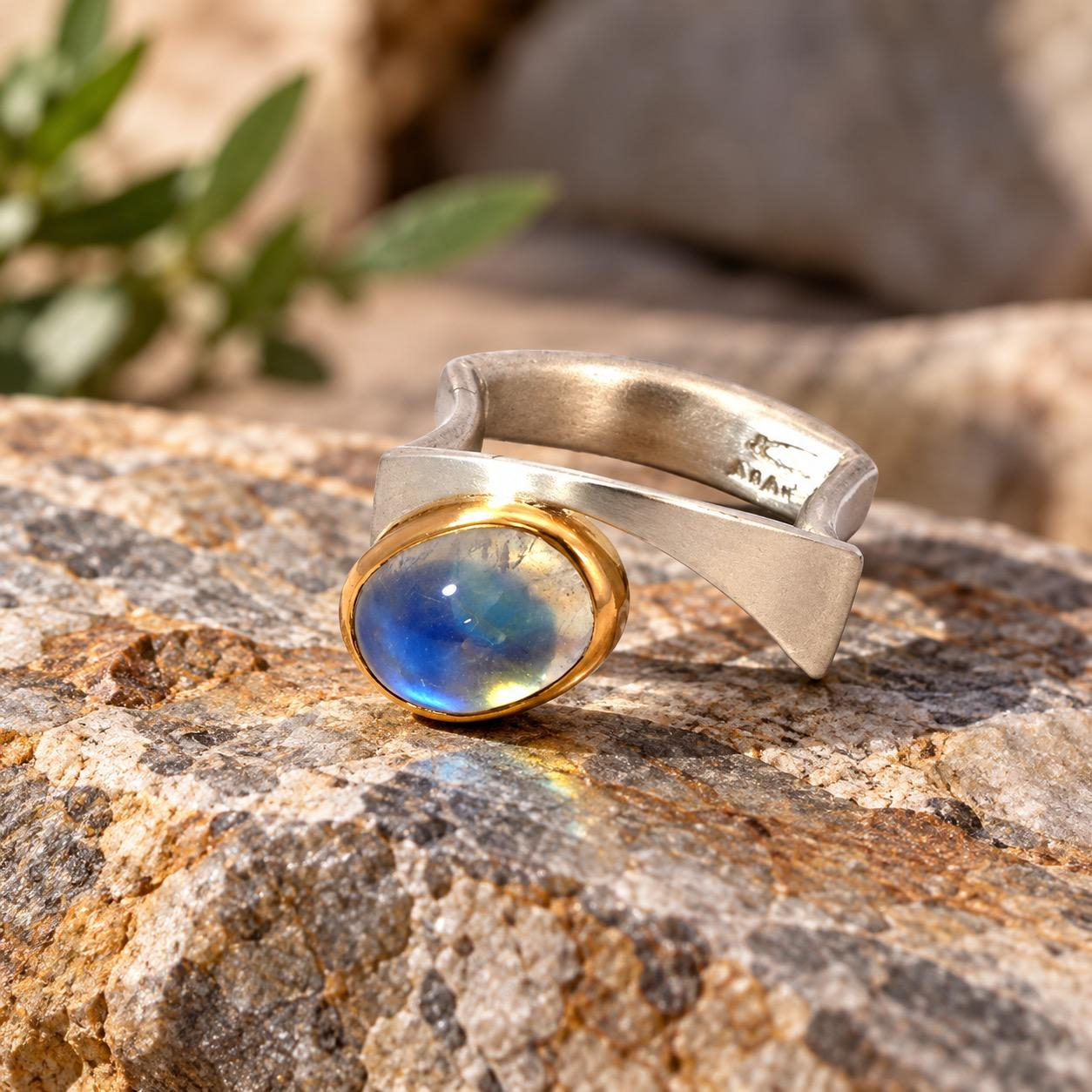 Smartcurve &ndash; Skulpturale Eleganz mit Mondstein
Der Smartcurve Ring vereint modernes Schmuckdesign mit der faszinierenden Sch&ouml;nheit eines schimmernden Mondsteins.
Seine au&szlig;ergew&ouml;hnliche, geschwungene Form aus Silber verleiht ihm einen architektonischen Charakter. Im Mittelpunkt steht ein ausdrucksstarker Mondsteincabochon, dessen geheimnisvolles Farbspiel zwischen Blau, Gr&uuml;n und sanften Goldt&ouml;nen changiert.
Die warme Goldfassung bildet einen edlen Kontrast zum k&uuml;hlen Silber und unterstreicht die nat&uuml;rliche Sch&ouml;nheit des Edelsteins.
Ein Ring wie eine kleine Skulptur &ndash; individuell, ausdrucksstark und zeitlos.
Ideal f&uuml;r Menschen, die au&szlig;ergew&ouml;hnlichen Designschmuck lieben und mit einem besonderen Schmuckst&uuml;ck ihre Pers&ouml;nlichkeit unterstreichen m&ouml;chten.