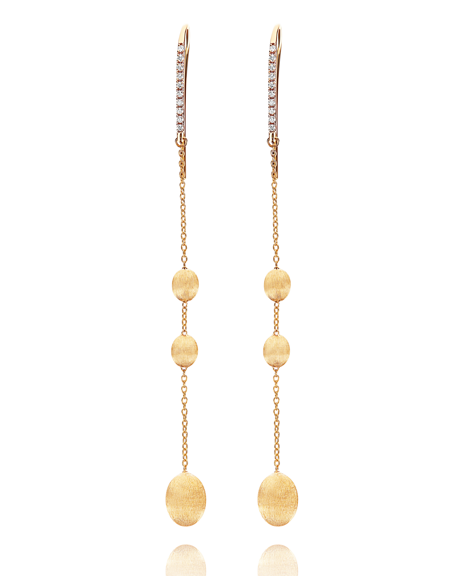 Pure Italiaanse luxe, met een elegante lichtheid die meteen de aandacht trekt. Deze lange oorhangers van Nanis zijn uitgevoerd in 18 karaat geelgoud en combineren fijne schakels met zacht afgeronde gouden elementen in verschillende formaten. Bovenaan zorgt een verfijnde rij diamanten voor een sprankelende toets, terwijl de lange lijnen sierlijk langs het gezicht bewegen. Het geheel voelt vrouwelijk, modern en bijna couture aan, zonder zijn draagbaarheid te verliezen. Perfect voor een avondlook, maar ook verrassend mooi als luxueus accent bij een sobere outfit.

Een uitgesproken Nanis-design met de nonchalante klasse van echte Italiaanse elegantie.