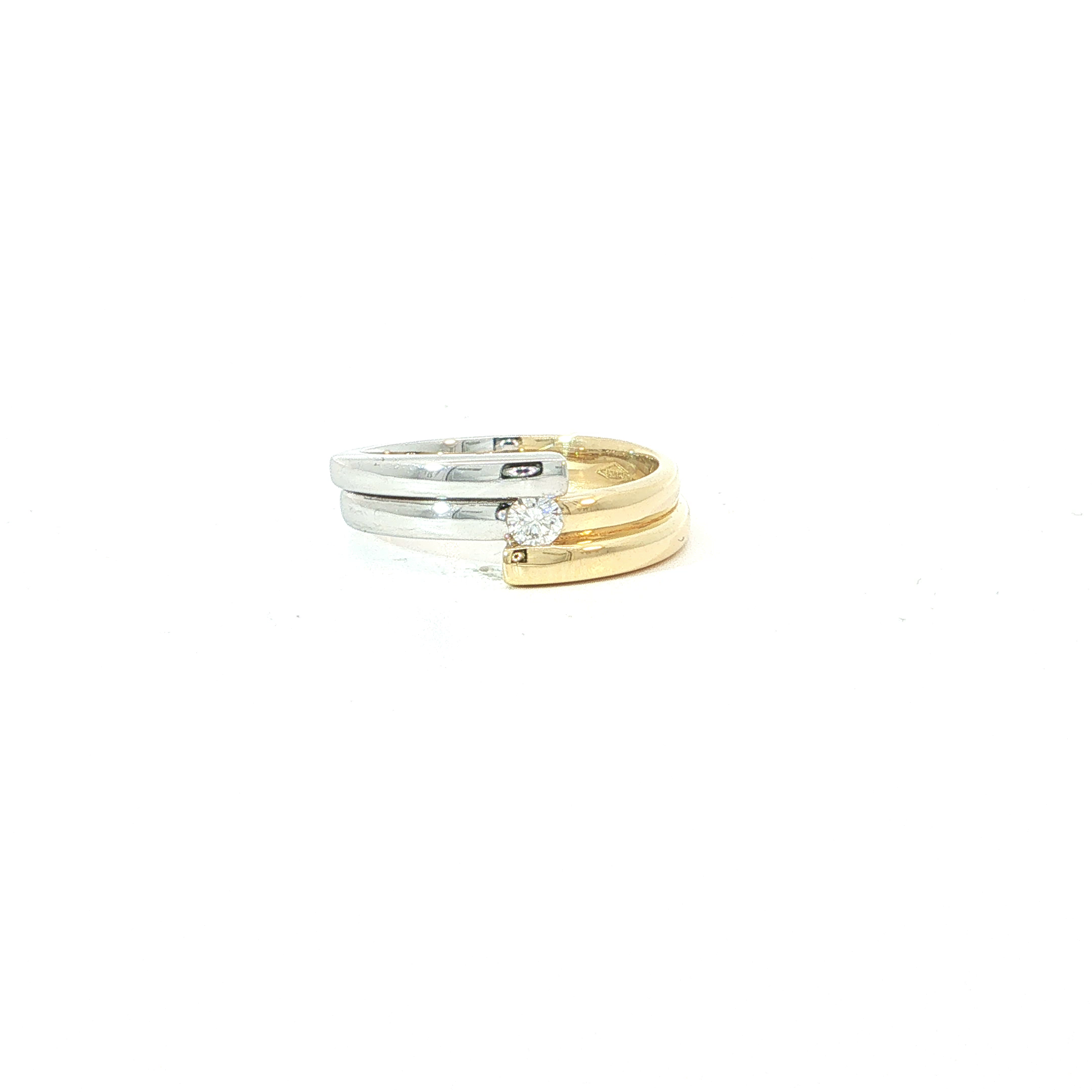 Een speels samenspel van twee kleuren goud, verenigd in &eacute;&eacute;n bijzonder ontwerp! 
Deze elegante ring in 18 karaat geel- en witgoud valt op door zijn sierlijk gelaagde vorm, waarbij de glanzende gouden banen elkaar op een verrassende manier aanvullen. Centraal schittert een prachtige briljant, subtiel omarmd door de vloeiende lijnen van het juweel. Het contrast tussen het warme geelgoud en het koele witgoud zorgt voor een moderne uitstraling met een verfijnde toets. Een ring met karakter, ideaal voor de vrouw die houdt van een origineel ontwerp zonder aan elegantie in te boeten. Een stijlvolle keuze die zowel dagelijks als bij feestelijke gelegenheden moeiteloos weet te verleiden.