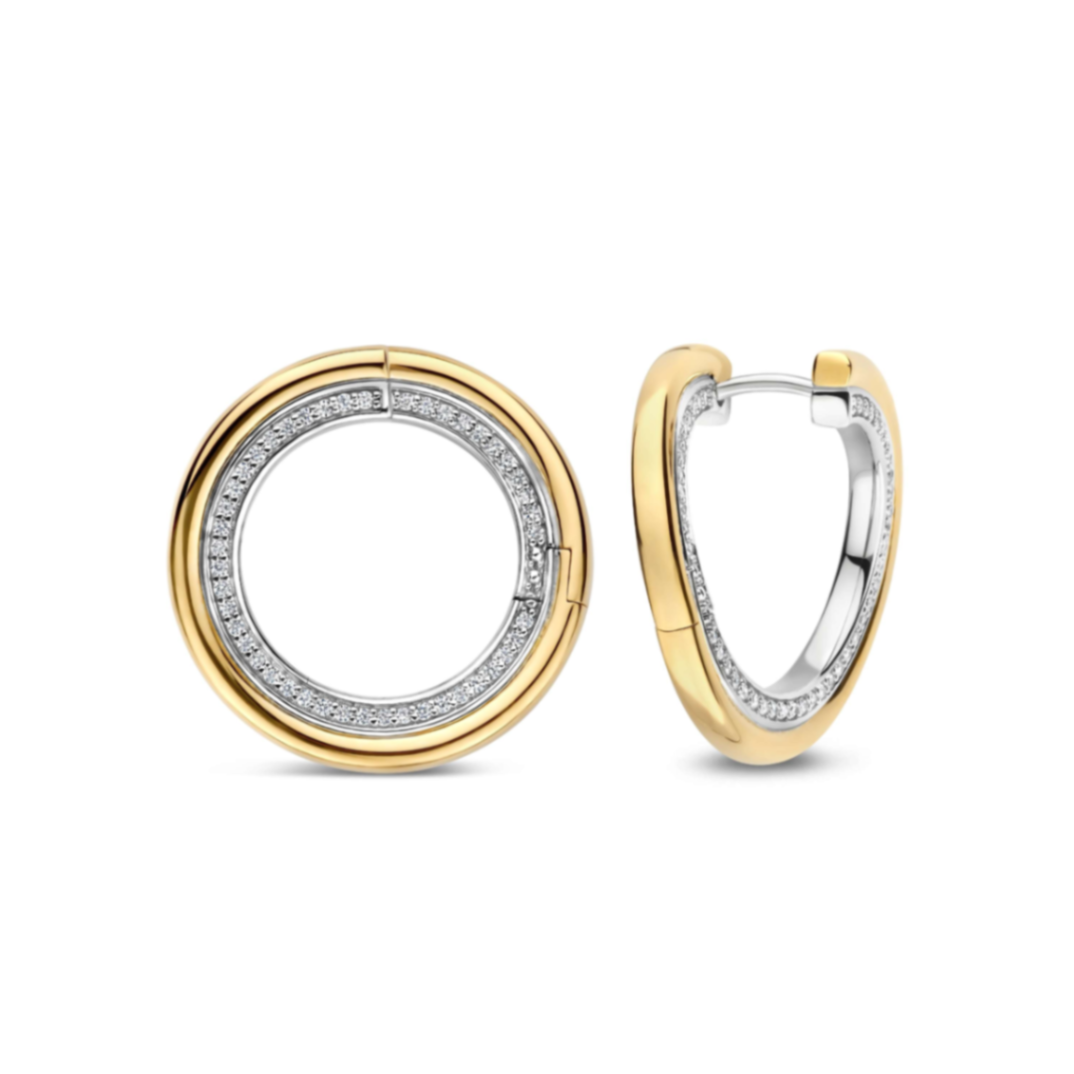 Deze verfijnde TI SENTO crossover oorringen combineren een modern silhouet met subtiele sprankeling. De oorbellen zijn vervaardigd uit hoogwaardige kwaliteit 925 sterling zilver en goudkleurig verguld. Het ontwerp bestaat uit een ronde vorm die is bezet met kleine fonkelende zirkonia steentjes. Wanneer de oorringen worden dichtgeklikt, vormen ze samen een strakke ronde vorm, wat het ontwerp een elegante en eigentijdse uitstraling geeft. Draag deze goudkleurig vergulde oorringen met zirkonia solo voor een verfijnde dagelijkse look of combineer ze met andere oorbellen voor een persoonlijke ear party. De ronde vorm en subtiele sprankeling maken deze oorbellen geschikt voor zowel een dagelijkse outfit als een meer geklede gelegenheid.